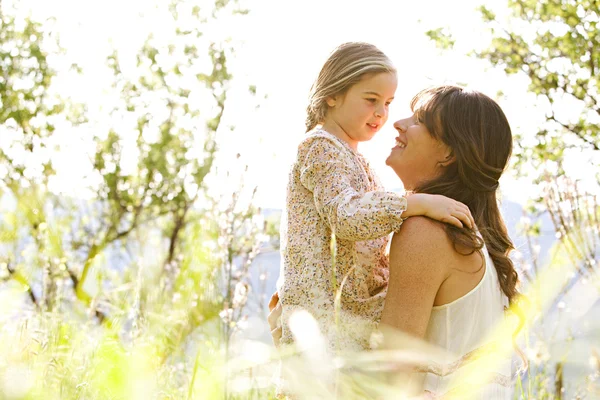 Mãe e filha abraçando em um campo de primavera — Fotografia de Stock