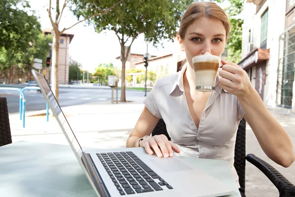 Business woman at a cafe using a laptop computer — Stockfoto