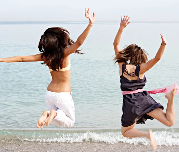 Girls jumping up in the air together on beach — Stockfoto