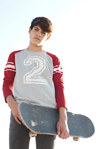 Adolescente ragazzo portando uno skateboard — Foto Stock