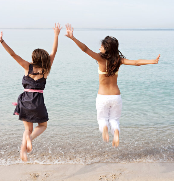 girls jumping up in the air together on beach