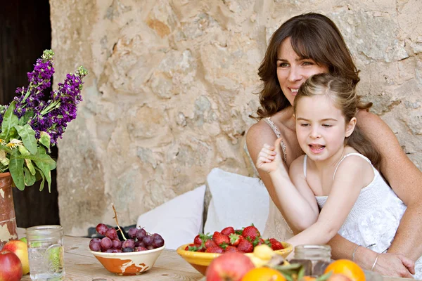 Madre e hija comiendo frutas en la mesa —  Fotos de Stock