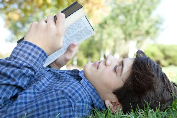 Student boy reading a book on grass — Stock Photo, Image