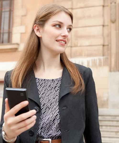 Mujer de negocios sonriendo y usando un teléfono inteligente —  Fotos de Stock