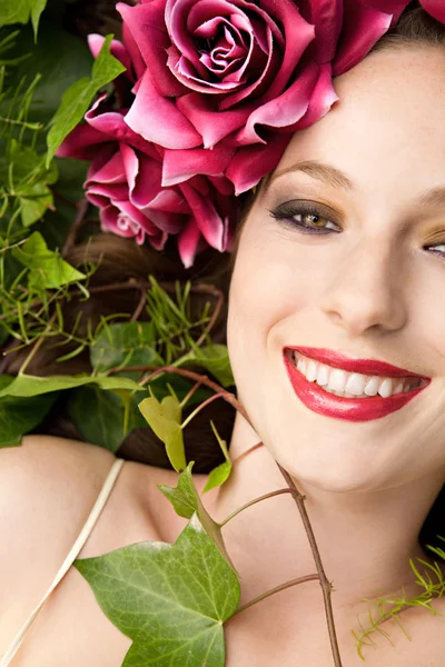 Woman laying in a forest wearing a red roses head dress — Stockfoto