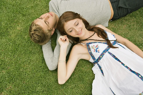 Couple laying down on green grass in a park — Stok fotoğraf