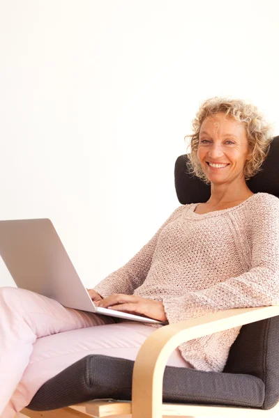 Mulher em uma poltrona usando um computador portátil — Fotografia de Stock