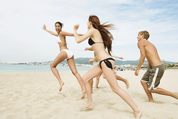 Friends running together towards the sea shore Rechtenvrije Stockfoto's