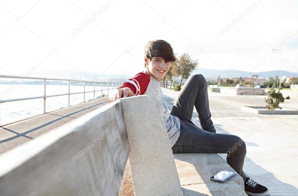 teeanger student relaxing on a bench by the sea