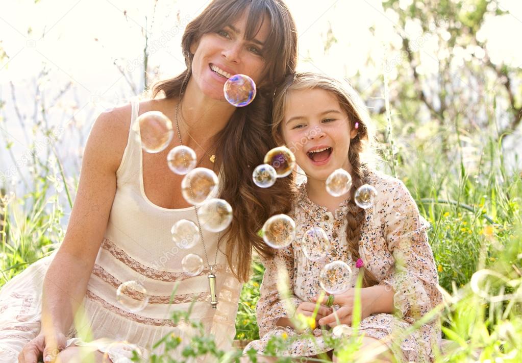 mother and daughter playing to blow floating bubbles