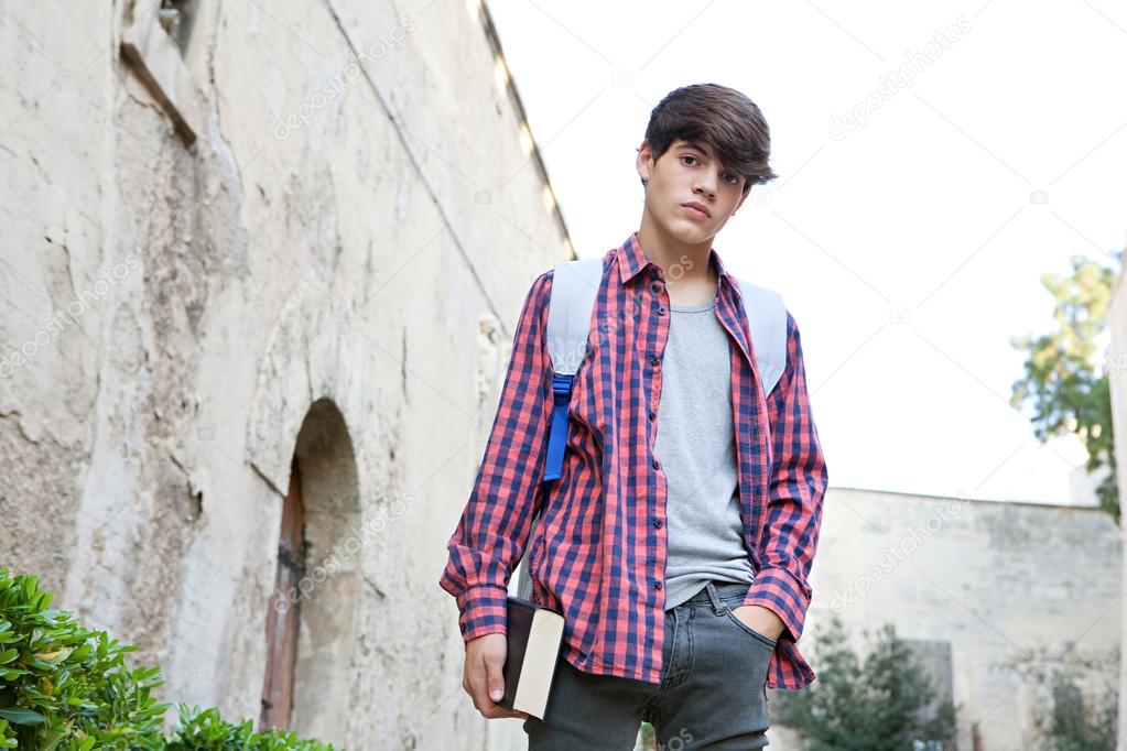 boy carrying a text book and a school backpack