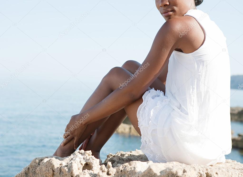 black woman sitting down on a natural rock platform