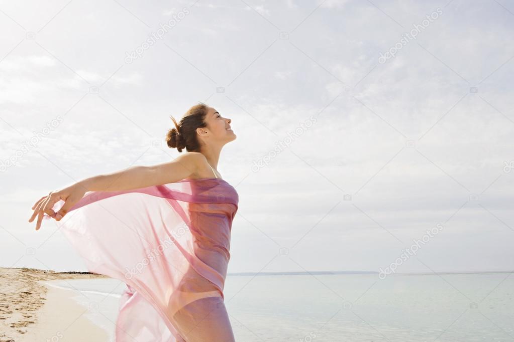 young woman with a pink fabric sarong on the beach