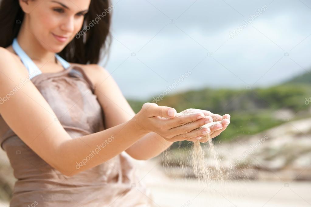 woman with sand grains filtering through her hands