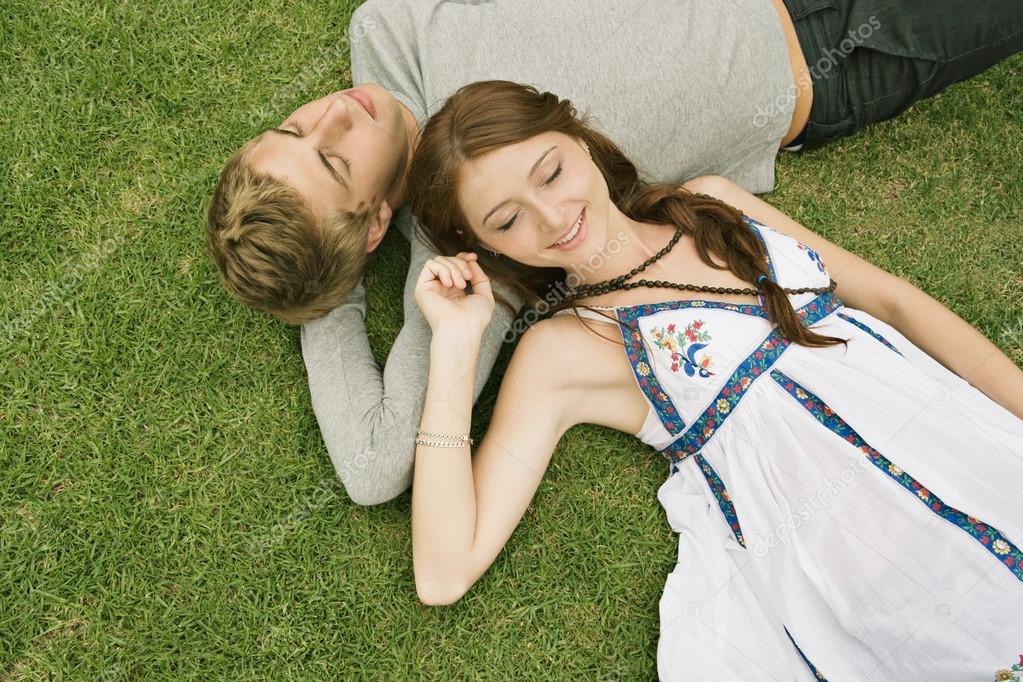 Couple laying down on green grass in a park — Stock Photo © mjth #79459660
