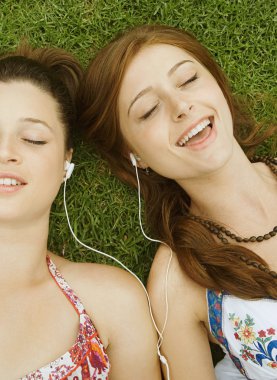 girls listening to music on green grass