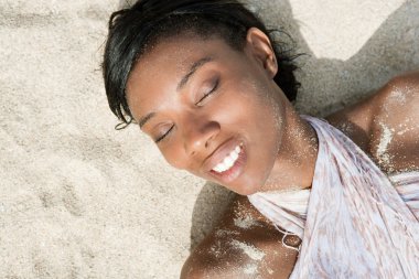 black woman laying on a sand beach