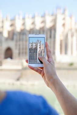 girl using a smartphone to take photos of a cathedral
