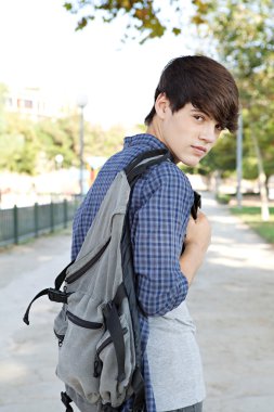 student boy walking on a path at a college campus