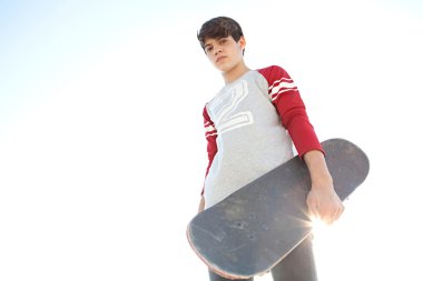 teenager boy carrying a skateboard