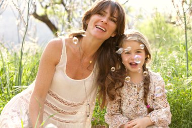 mother and daughter playing to blow floating bubbles