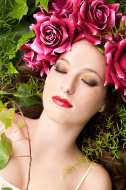 woman laying in a forest wearing a red roses head dress