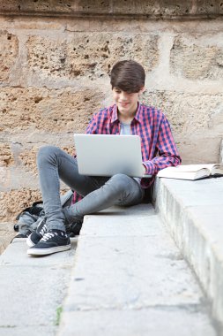 boy with school books and a laptop computer doing his homework