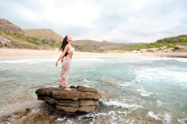 woman standing on a rock by the sea