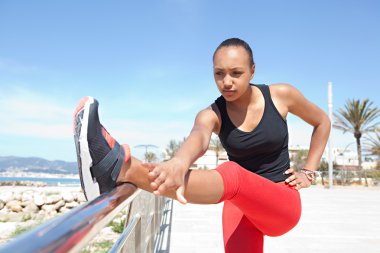 woman stretching her legs leaning on metallic railings