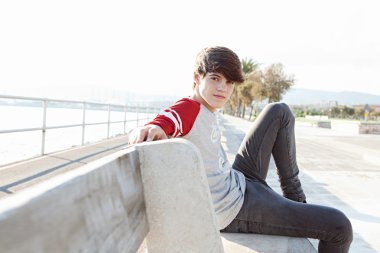 boy relaxing and sitting on a bench by the sea