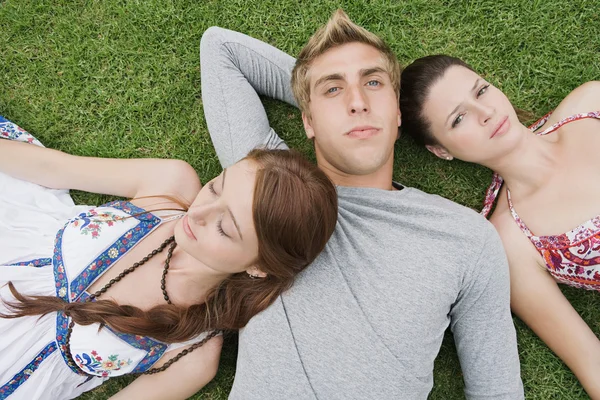 Friends laying down on green grass in a park — Φωτογραφία Αρχείου