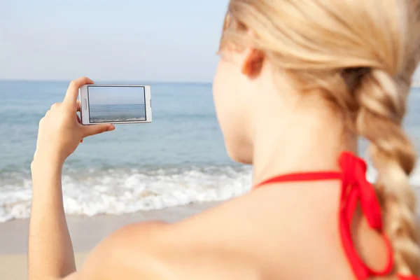 Žena pomocí smartphone na pláži — Stock fotografie