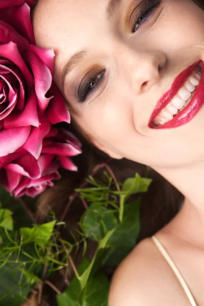 Mulher deitada em uma floresta usando um vestido de cabeça de rosas vermelhas — Fotografia de Stock