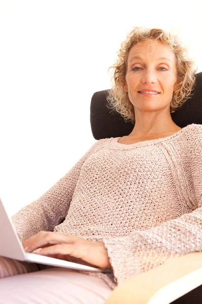 Mulher em uma poltrona usando um computador portátil — Fotografia de Stock