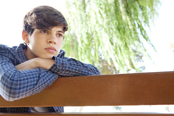 Boy sitting and relaxing on a park wooden bench — Φωτογραφία Αρχείου