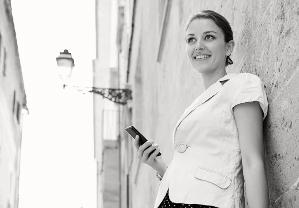 Mujer de negocios sosteniendo un teléfono inteligente y sonriendo — Foto de Stock