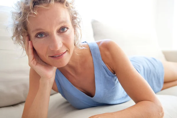 Woman relaxing on a white sofa at home — Stok fotoğraf