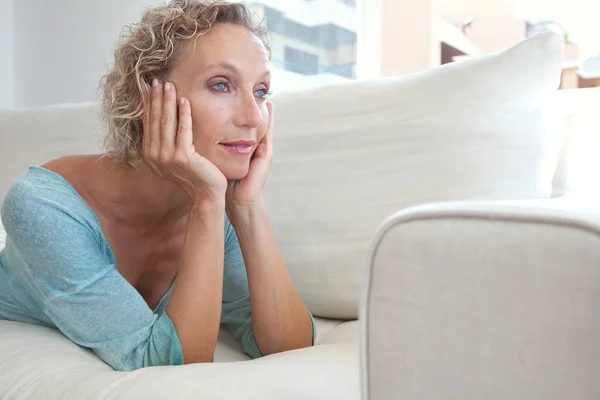 Woman on a white sofa at home — ストック写真