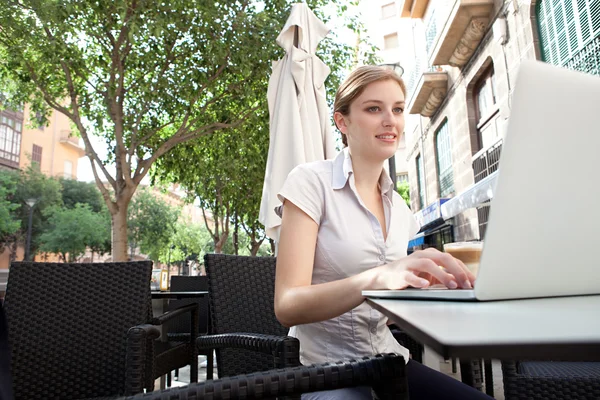 Business woman at a cafe using a laptop computer — Stockfoto