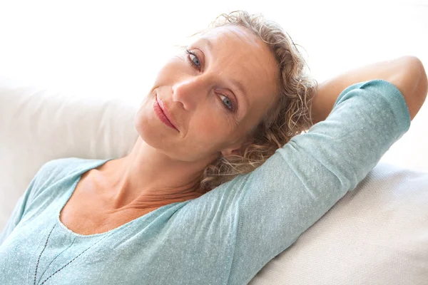 Woman on a white sofa at home — Stockfoto