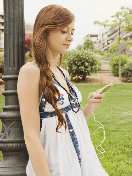 Girl using a mp4 player in park — Stockfoto
