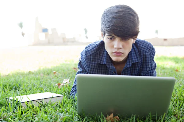 Jongen met behulp van een laptopcomputer op een gras — Stockfoto