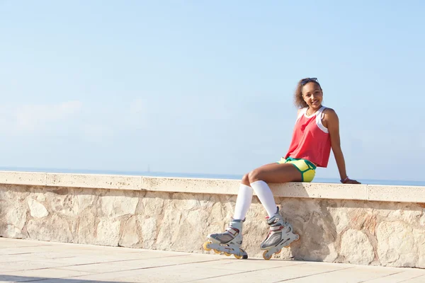 Girl relaxing with her roller skates by the beach — Stockfoto