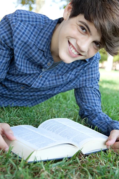 十几岁男孩在草地上读书 — 图库照片