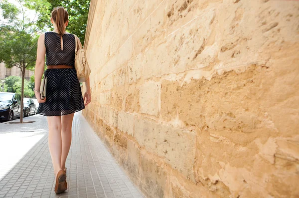 Donna d'affari che cammina lungo un vecchio muro di pietra — Foto Stock