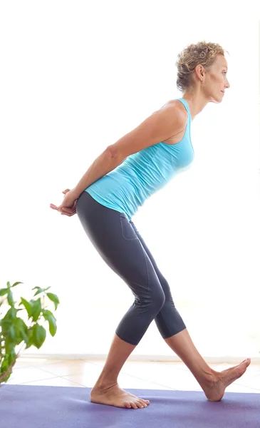 Mujer usando una esterilla de yoga para ejercitar y estirar su cuerpo —  Fotos de Stock