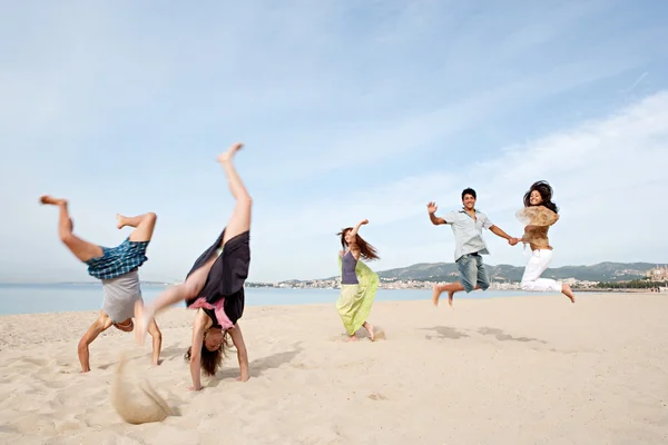 Friends jumping and doing cartwheels celebrating the summer holidays — Stockfoto