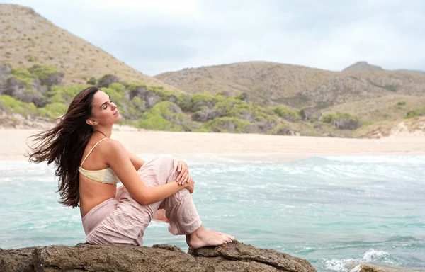 Mujer sentada en una roca junto al mar — Foto de Stock