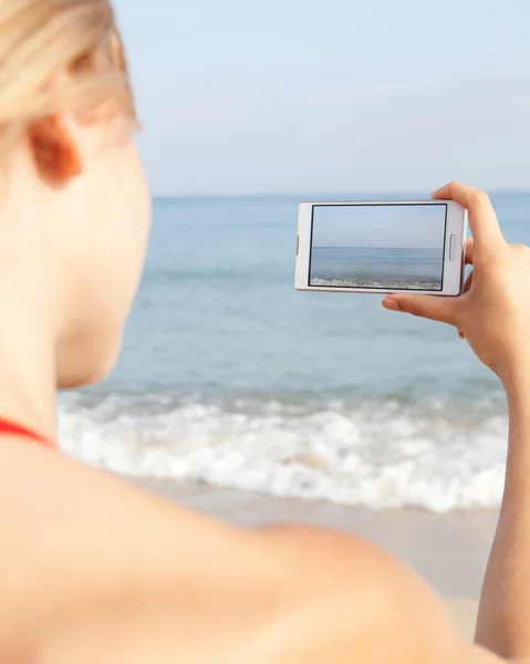 Vrouw met smartphone op het strand — Stockfoto