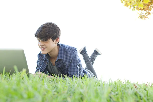 Ragazzo che utilizza un computer portatile su un'erba — Foto Stock